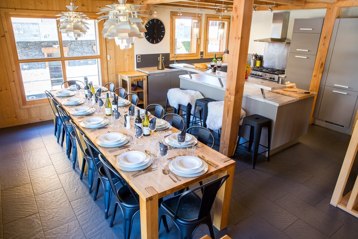 A long dining table with a clock on the wall above it