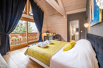 A bedroom with a large bed and a balcony