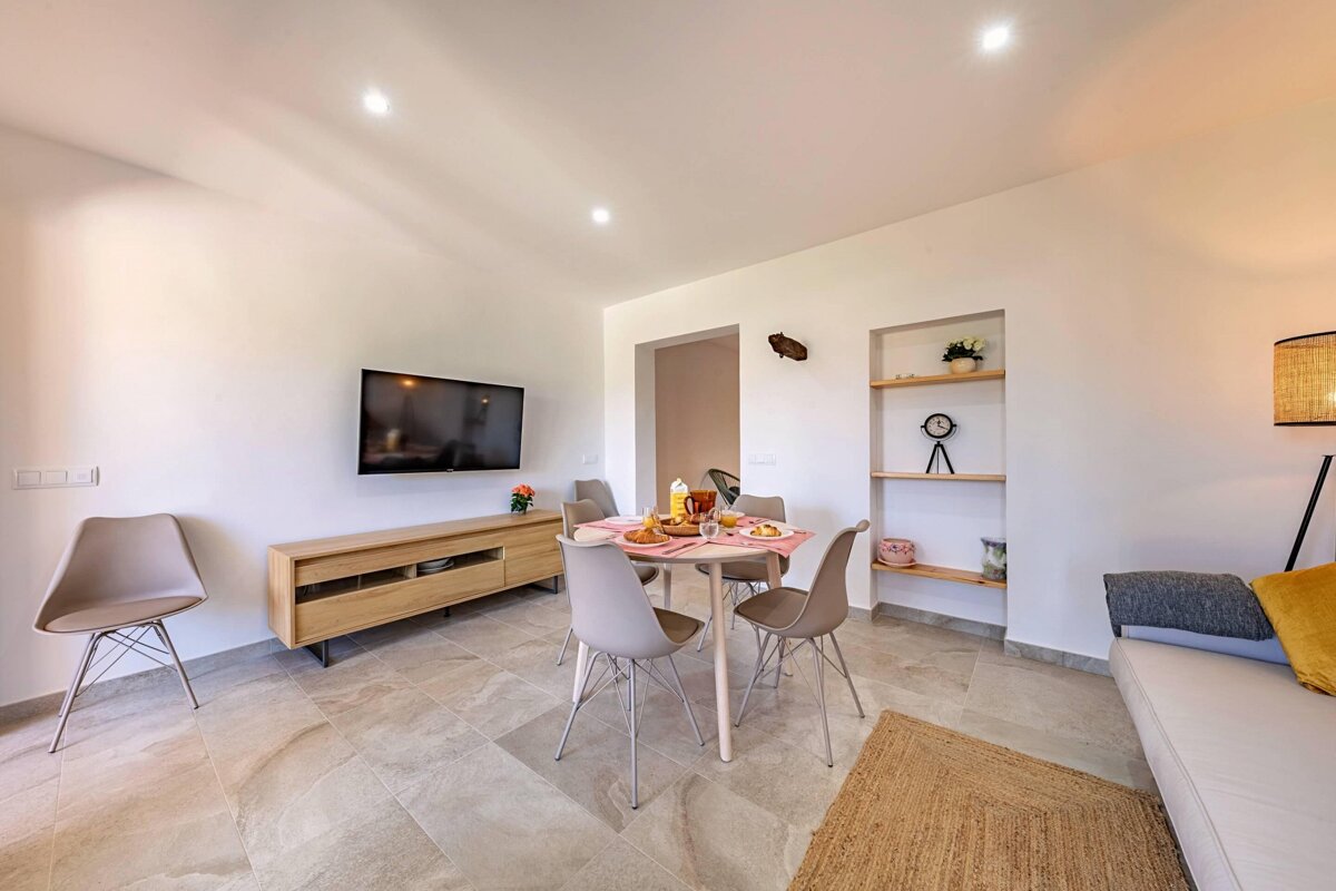 A living room with a table and chairs and a flat screen tv