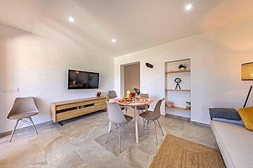 A living room with a table and chairs and a flat screen tv