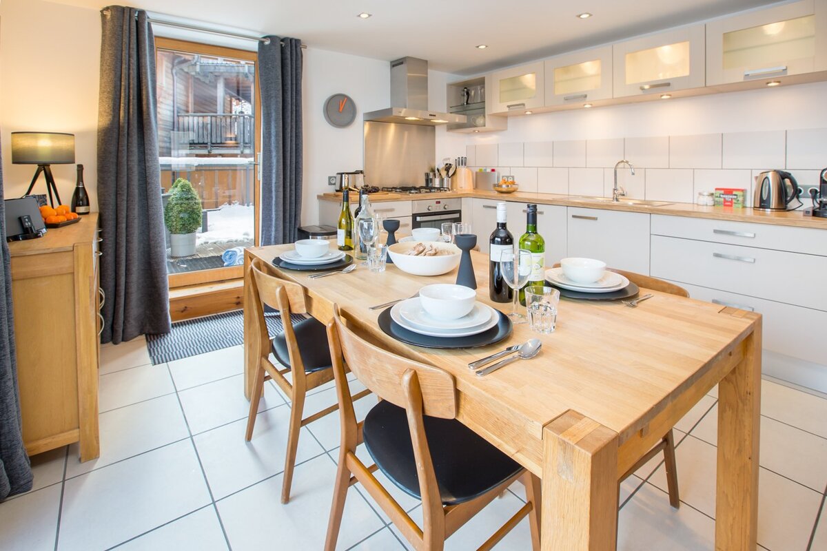 A kitchen with a table and chairs and a clock on the wall