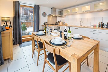 A kitchen with a table and chairs and a clock on the wall