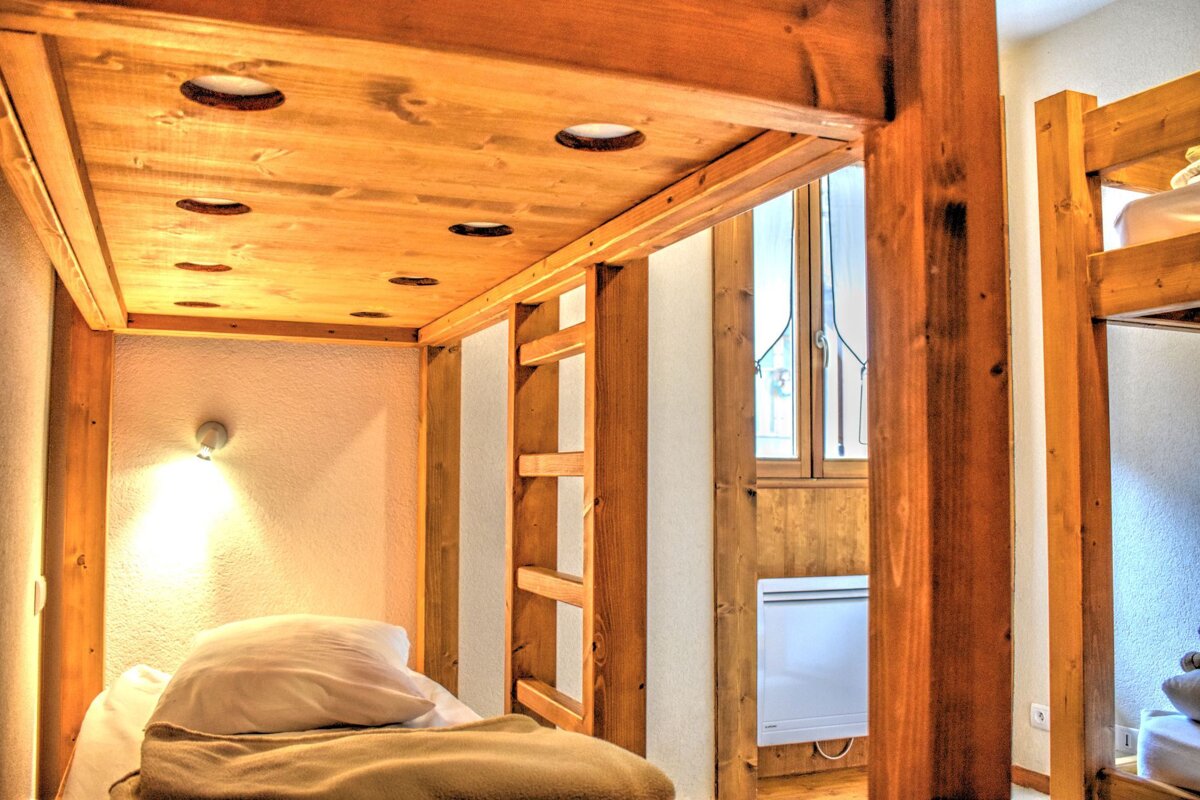 A wooden bunk bed with a white blanket on it