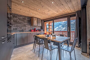 A kitchen with a table and chairs and a view of the mountains