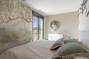 A bedroom with a large window and a painting on the wall