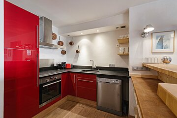 A kitchen with red cabinets and a stainless steel dishwasher