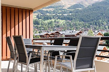 A table and chairs on a balcony with mountains in the background