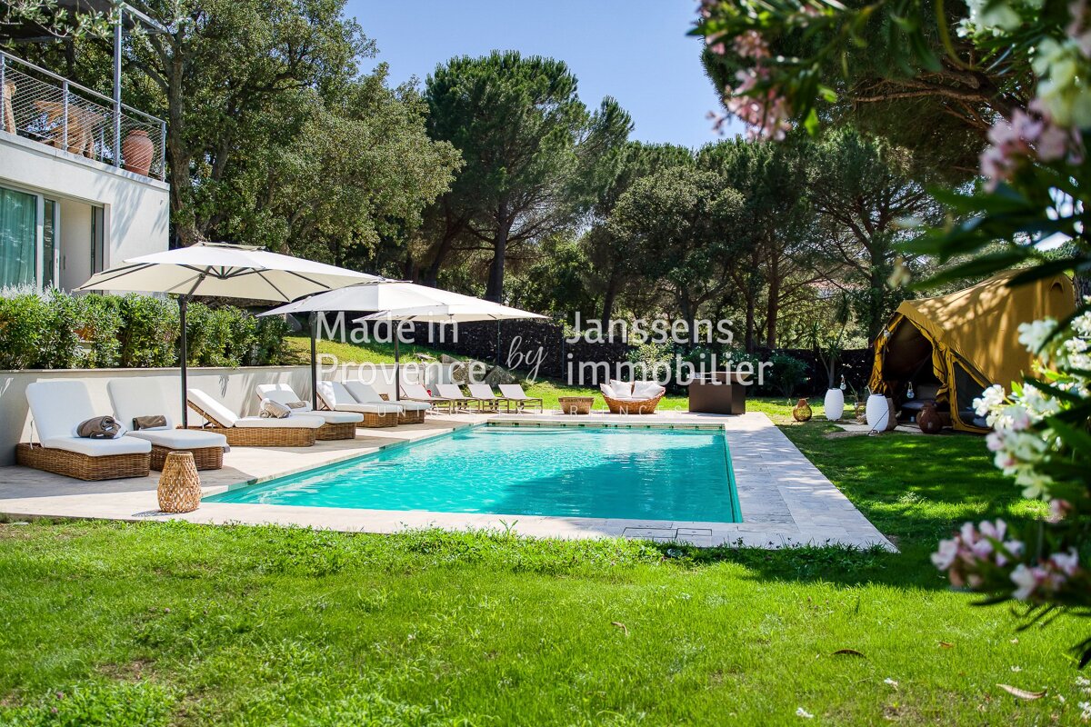 A large swimming pool is surrounded by lawn chairs and umbrellas and says made in provence by immobilier