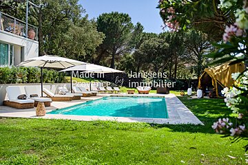 A large swimming pool is surrounded by lawn chairs and umbrellas and says made in provence by immobilier