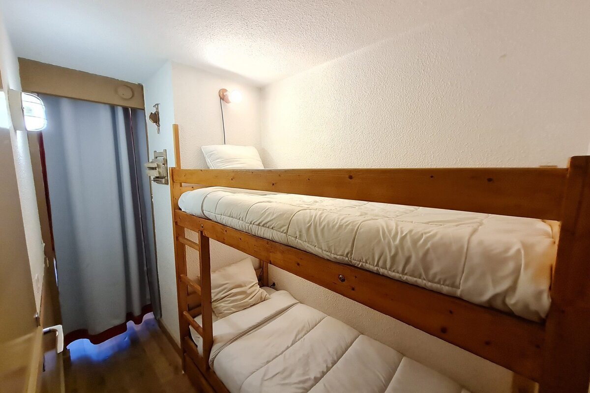 A wooden bunk bed with white sheets and pillows
