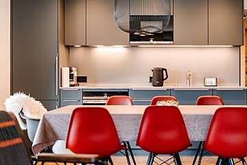 A kitchen with grey cabinets and red chairs