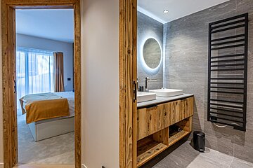 A bathroom with two sinks and a round mirror