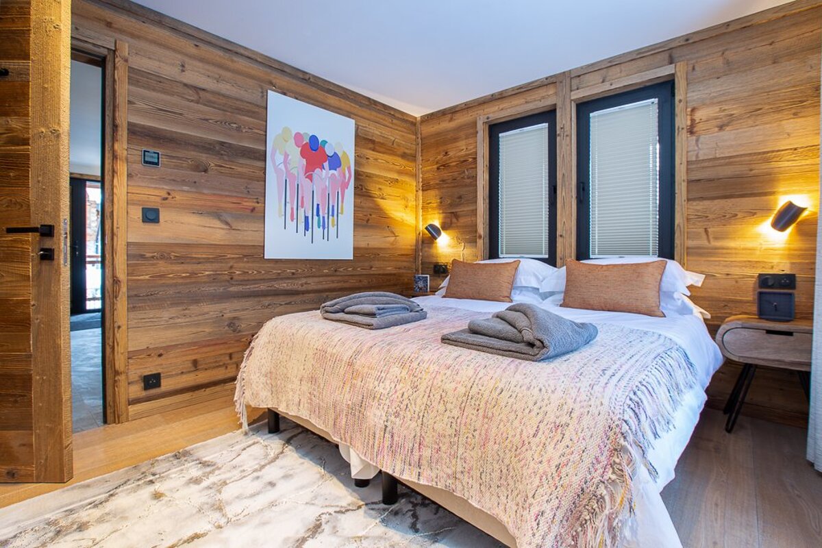 A bedroom with a painting on the wall above the bed