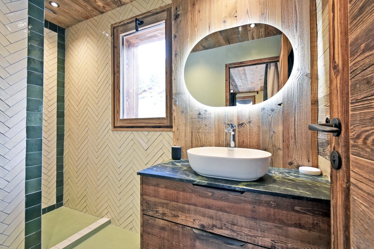 A bathroom with a sink and a round mirror