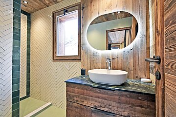 A bathroom with a sink and a round mirror