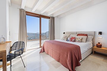 A bedroom with a large bed and a sliding glass door