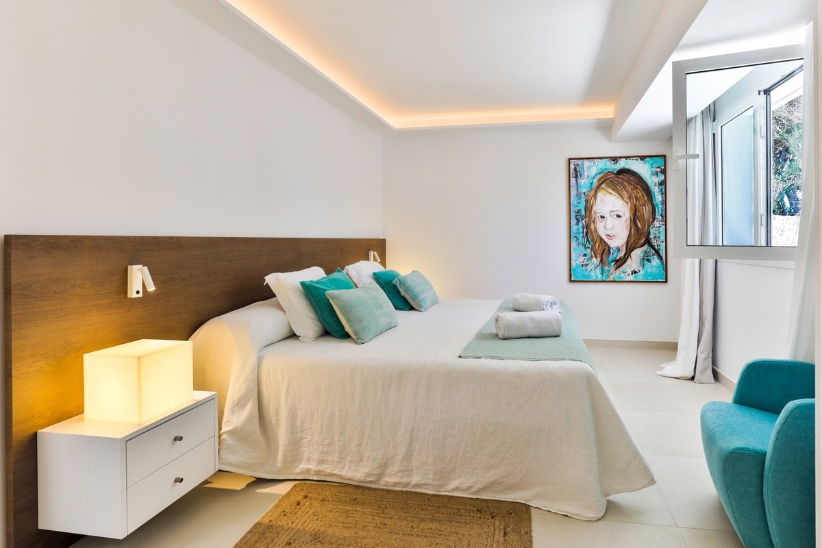 A bedroom with a painting on the wall above the bed