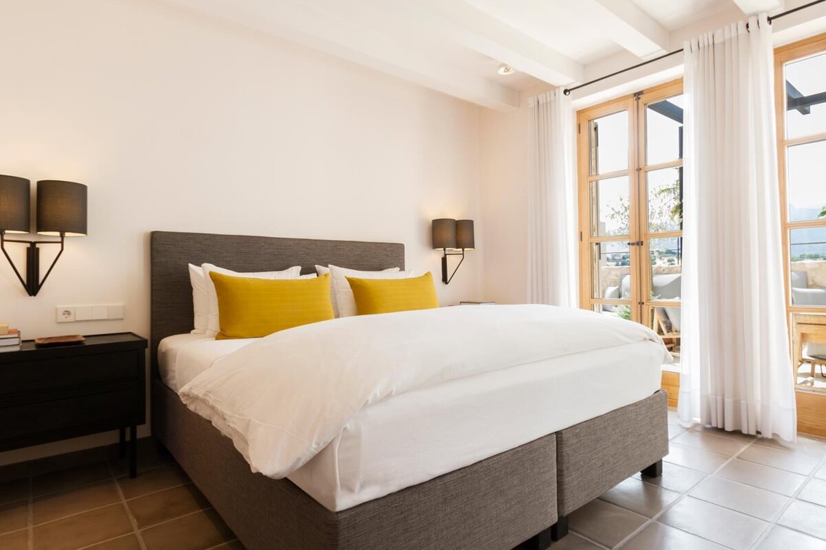 A bedroom with a bed and two lamps on the wall