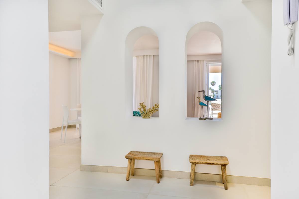 A hallway with two stools and a mirror on the wall