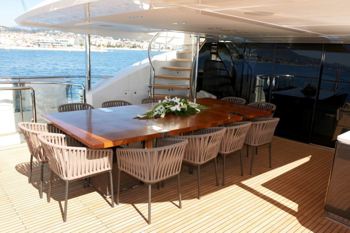 A large wooden table and chairs on the deck of a boat
