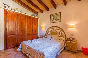 A bedroom with a wicker headboard and wooden cabinets