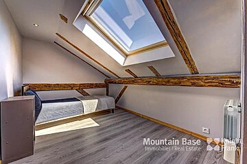 A bedroom with a bed and a skylight from mountain base immobilier real estate