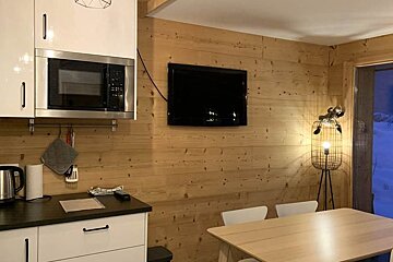 A kitchen with a microwave and a flat screen tv