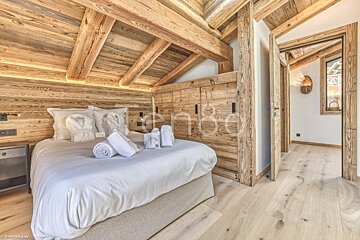 A bedroom with wooden walls and a bed with white sheets