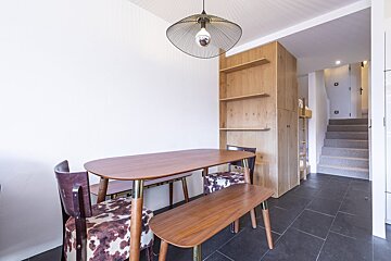 A dining room with a table and chairs and a staircase in the background