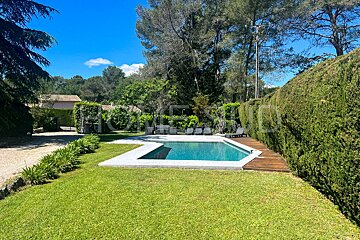 A large swimming pool in the middle of a lush green yard