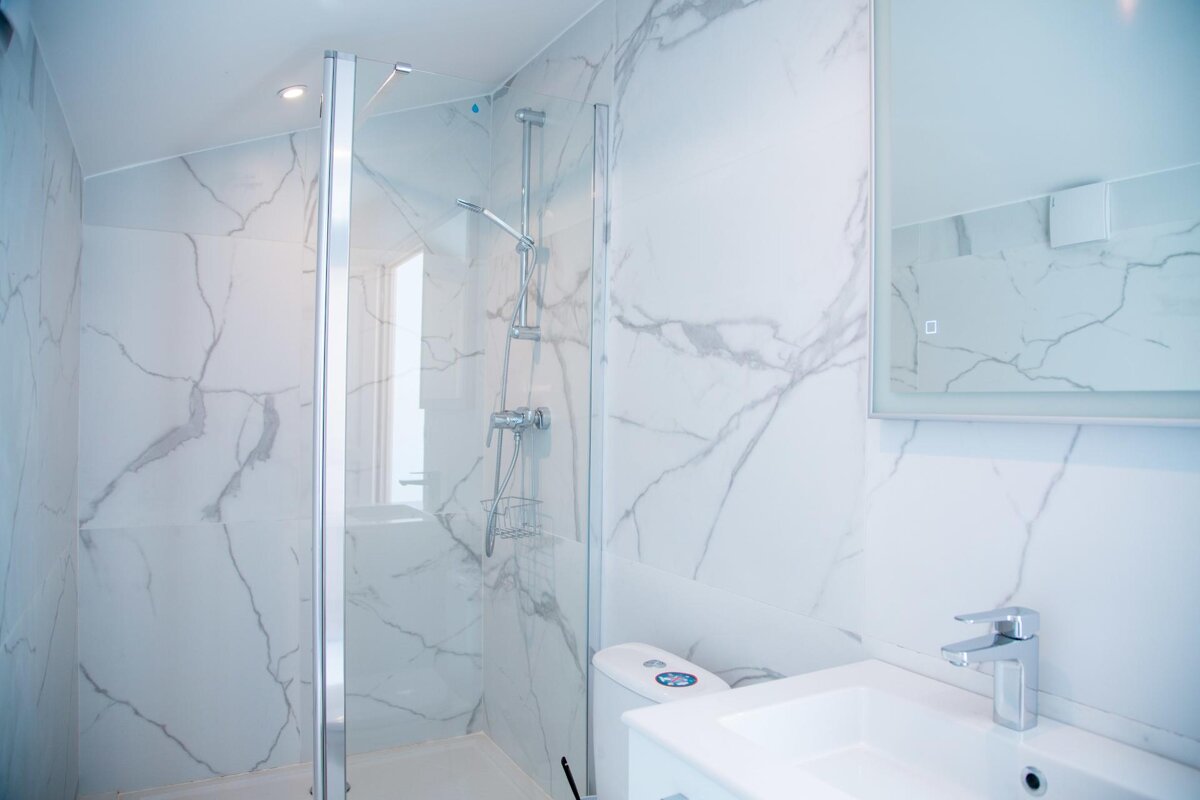 A bathroom with marble walls and a walk in shower