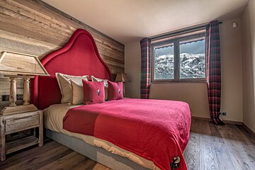 A bedroom with a bed and a window with mountains in the background