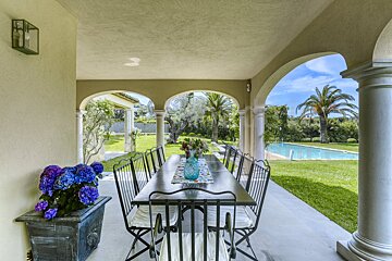 A table and chairs on a porch with a pool in the background