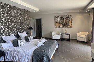 A bedroom with a painting on the wall above the bed