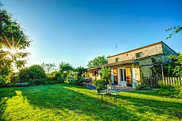 The sun is shining brightly on the grass in front of a house