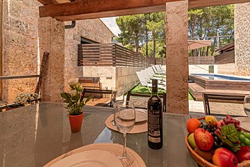 A bottle of wine sits on a table next to a basket of fruit