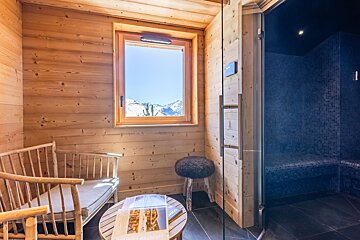 Cozy wooden relaxation room with a scenic mountain view next to a blue-tiled steam room.