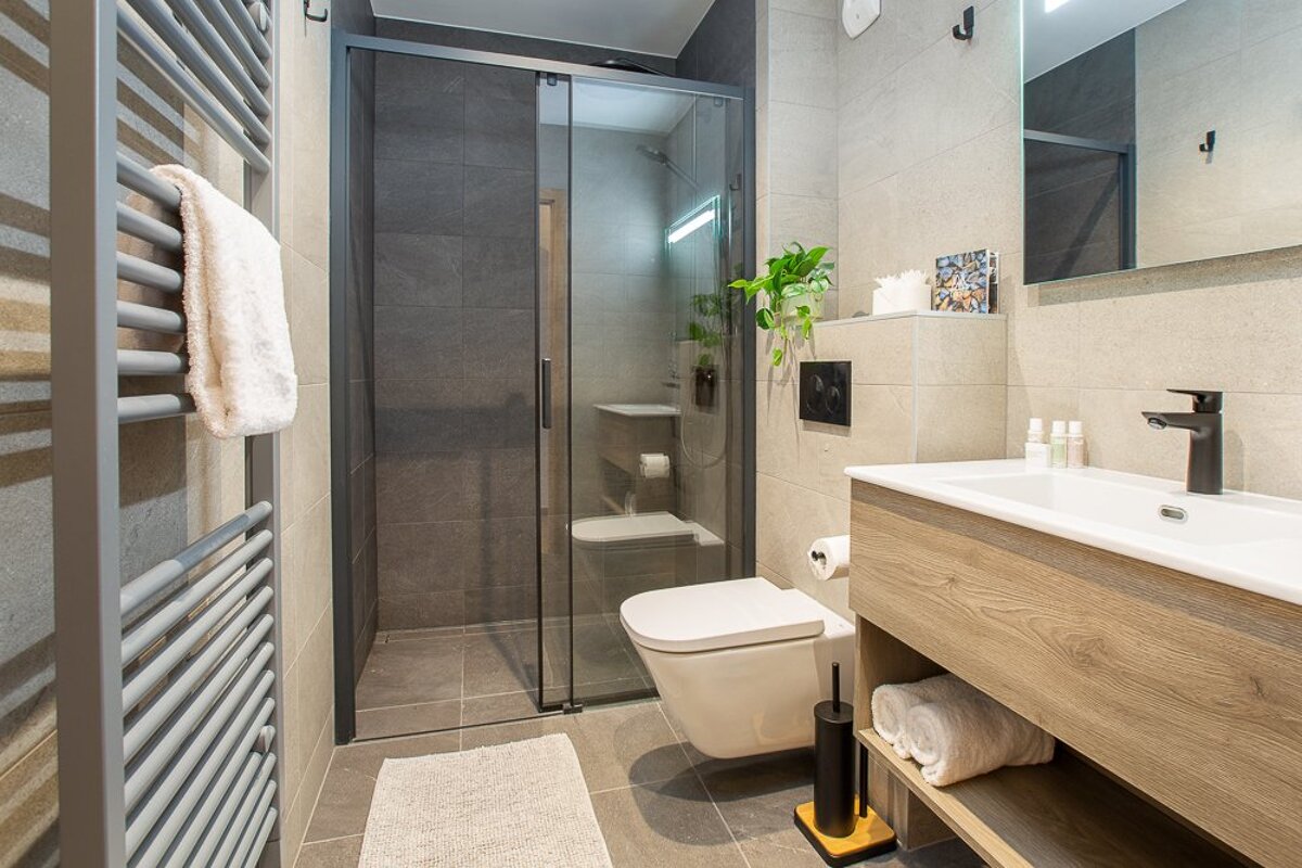 A bathroom with a toilet a sink and a walk in shower