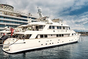 A large white yacht is docked in a harbor