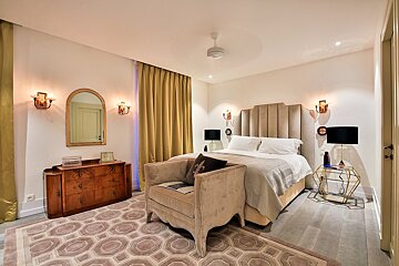 A bedroom with a bed a chair a dresser and a mirror