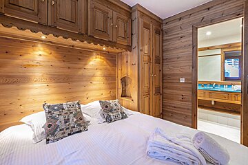 A bedroom with wood paneling and a large bed