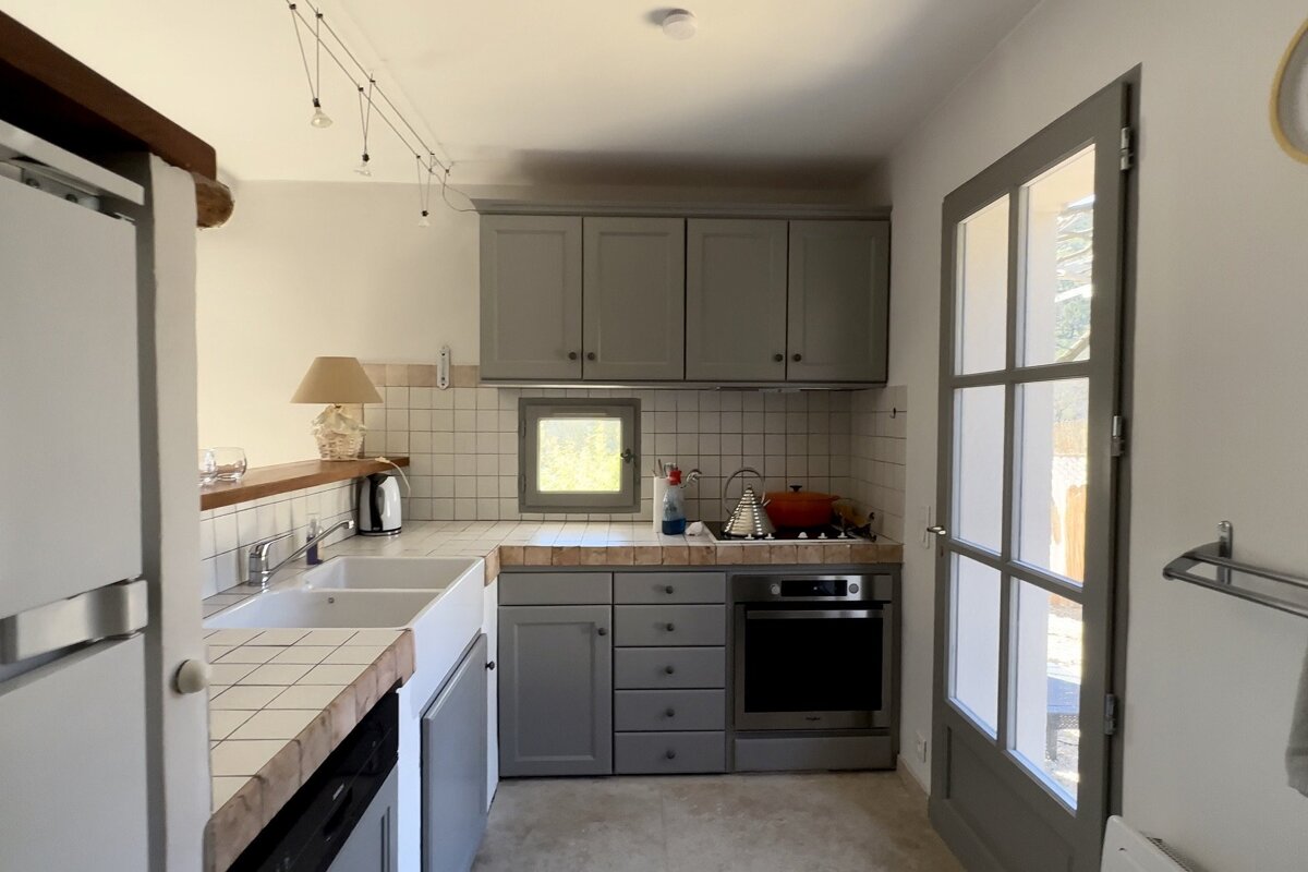 A kitchen with gray cabinets and white counter tops