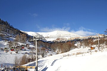 A ski lift is going up a snowy mountain