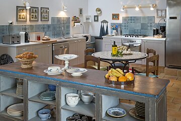 A kitchen with a table and chairs and a bottle of wine on it
