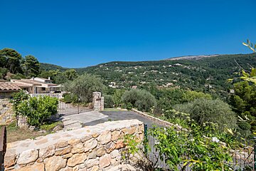 A stone wall surrounds a house in the mountains