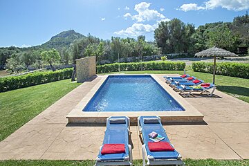 A large swimming pool surrounded by lawn chairs and umbrellas