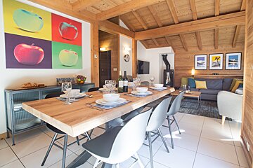 A dining room with a table and chairs and a painting of apples on the wall