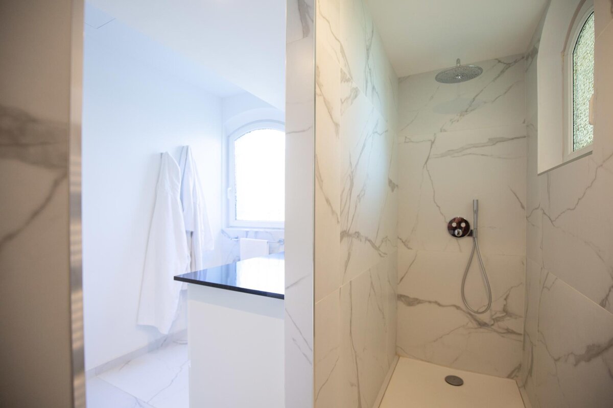 A bathroom with marble tiles and a walk in shower