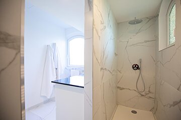 A bathroom with marble tiles and a walk in shower