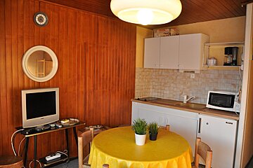 A small kitchen with a yellow table and a tv